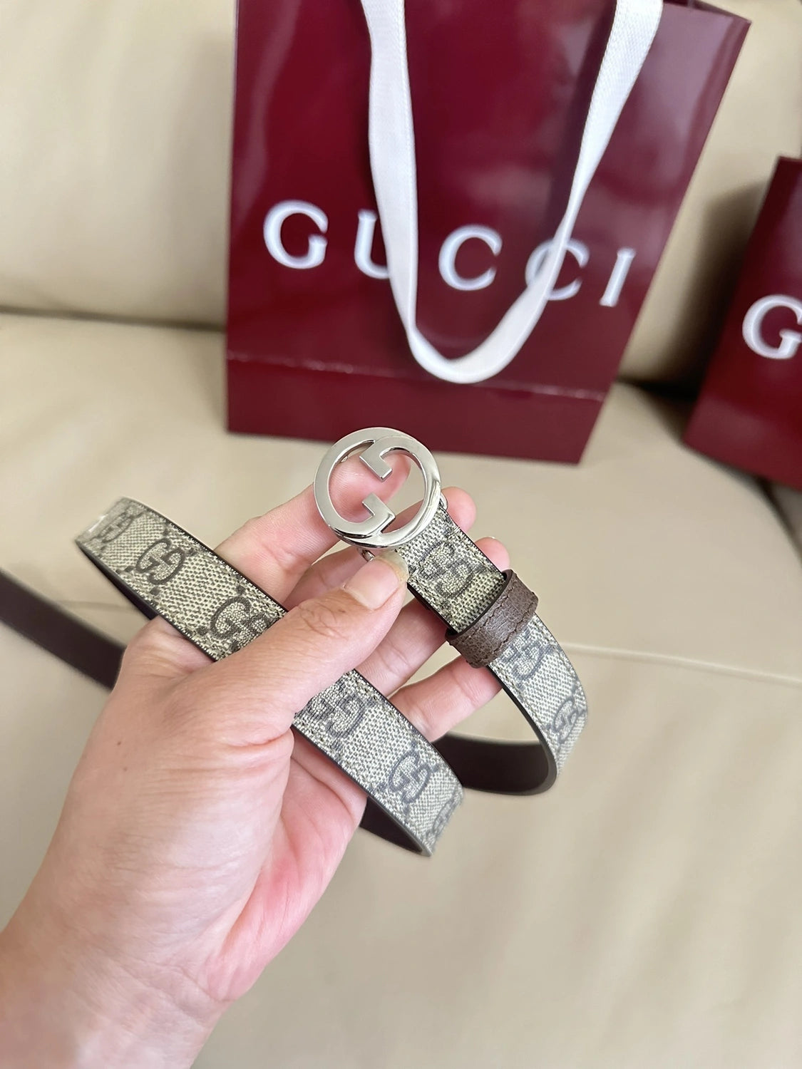 Gucci belt with GG logo buckle on beige background