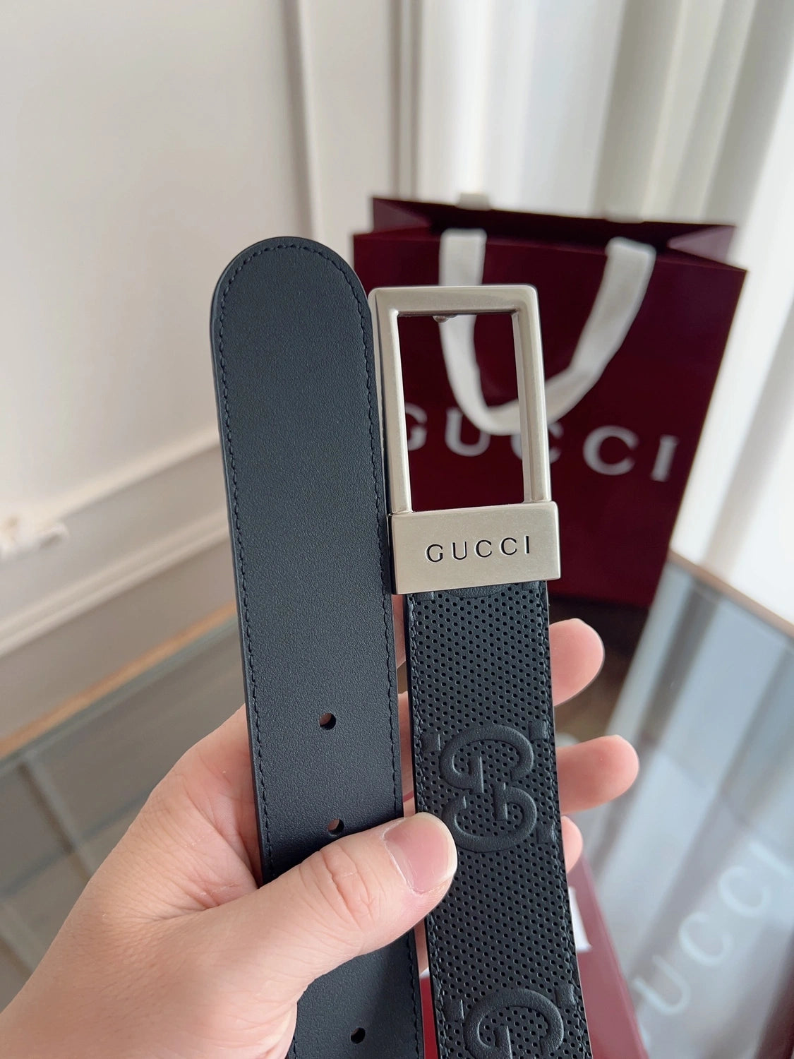 Close-up of a black Gucci premium leather belt with silver buckle.